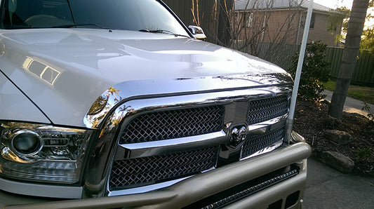 Chrome bonnet protector for RAM 2500 and 3500 trucks, designed by Geared for Adventure, visible on a vehicle in the image.